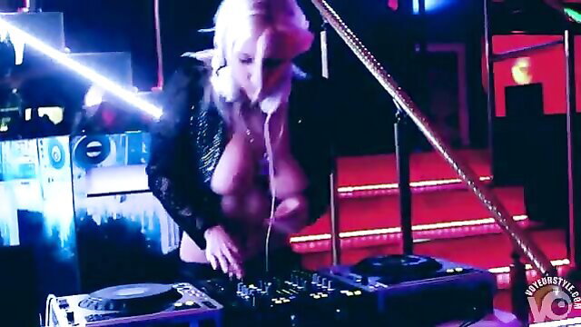 Topless blonde DJ dances seductively while spinning records