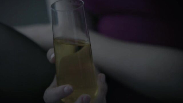 Bree Daniels holds champagne glass in dim light, short hair tease