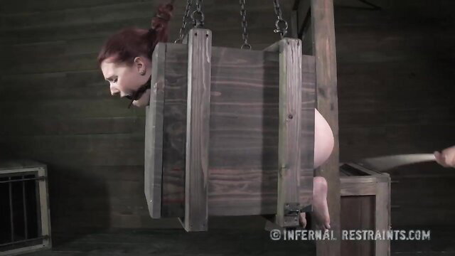 Redhead bound in wooden device endures whipping by master