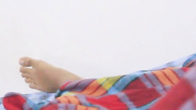 Hot Sri Lankan stepsister's bare foot peeking from colorful blanket in bed