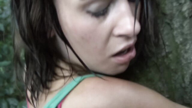 Closeup of young brunette woman with wet hair, aroused expression outdoors