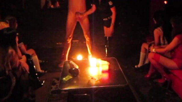 Nude male slave surrounded by sexy women in lingerie at fetish party