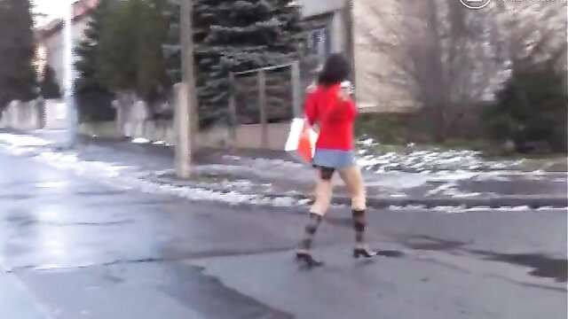 Brunette in red mini skirt, pantyhose, boots walking on snowy street