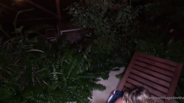 Sage Dovina blonde in skimpy top bent over lounge chair outdoor night