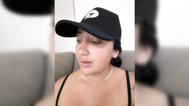 Hannahoff in black cap and top, teasing cleavage on webcam