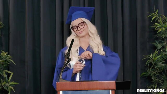 Elsa Jean as sexy grad student at podium in cap and gown