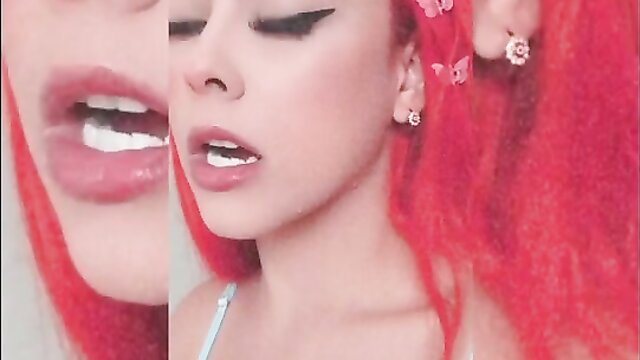 Closeup of busty redhead cam girl's glossy open mouth and teasing tongue