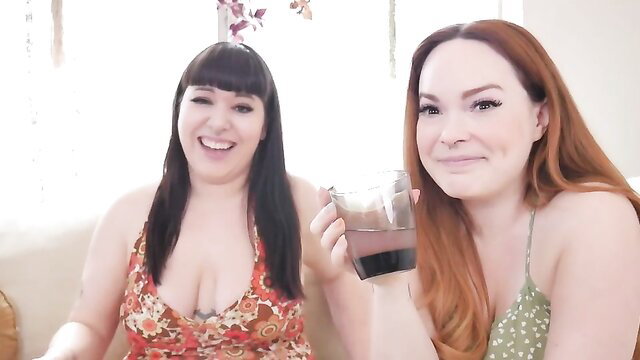 Two busty MILFs with black and red hair smiling with drinks