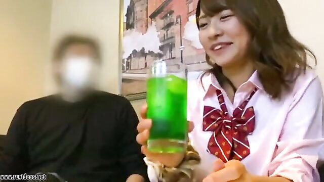 Japanese schoolgirl in uniform holds green drink with blurred man, JAV tease