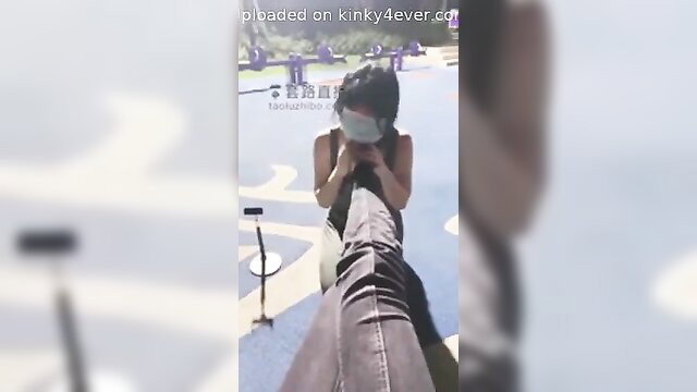 Asian woman in mask worships cock outdoors with feet
