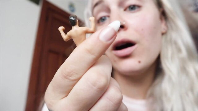 Blonde giantess holds tiny man toy, teasing blowjob closeup