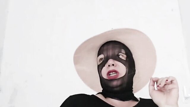 Mystery woman in sheer black hood mask and wide hat, seductive gaze