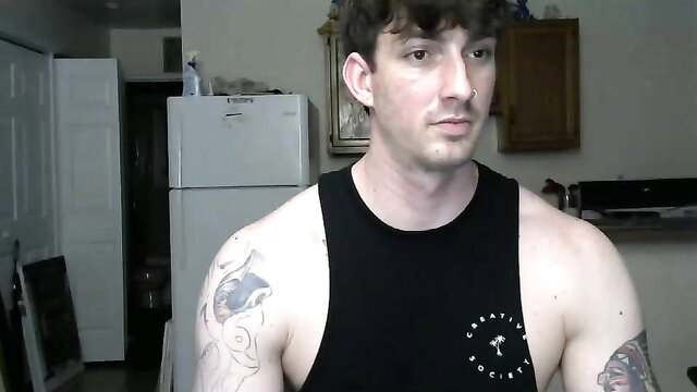 Tattooed muscular guy in tank top, intense gaze in amateur video thumbnail