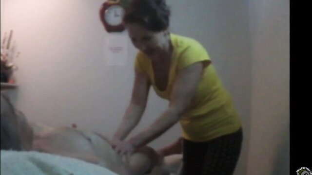 Asian masseuse in yellow top gives oily handjob to nude male client