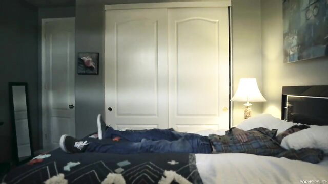 Bridgette B as Aunt Bridgett lying on bed in jeans and plaid shirt