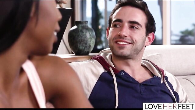 Black babe flirts with white guy on couch in interracial foot fetish scene