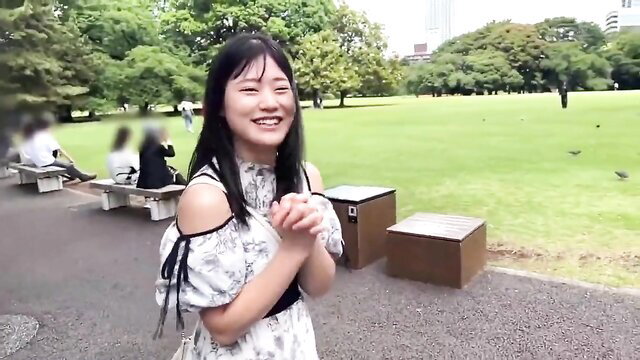 Smiling Japanese athlete in off-shoulder dress prays in park