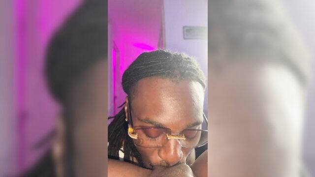 Closeup of black man with dreads and glasses smirking intimately