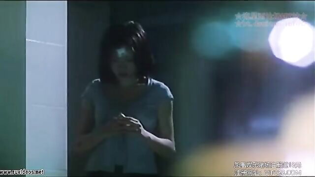 Asian woman in tank top holding phone in dark bathroom scene from Hong Kong erotic thriller