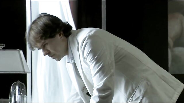 Handsome man in white suit leans forward in erotic scene