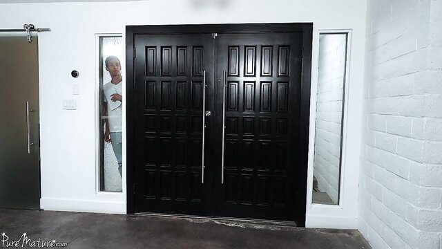 Silver-haired mature neighbor peeking through door in tight white tee and jeans