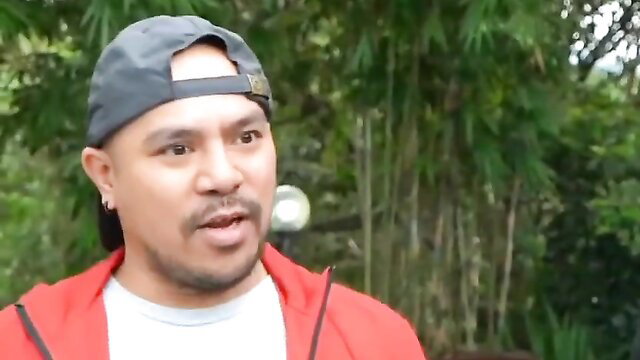 Handsome Asian man in red hoodie and cap smiles outdoors, adult taste test preview