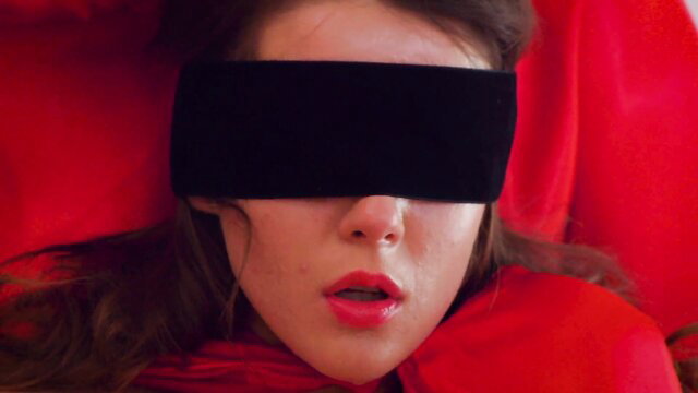 Blindfolded brunette with red lips in erotic red scene