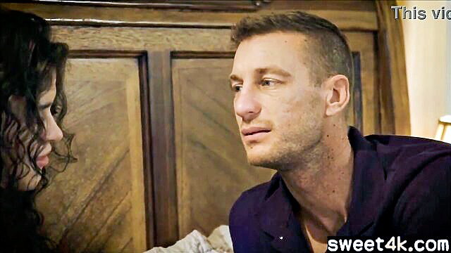 Curly-haired brunette woman gazes at handsome man in intimate bedroom chat