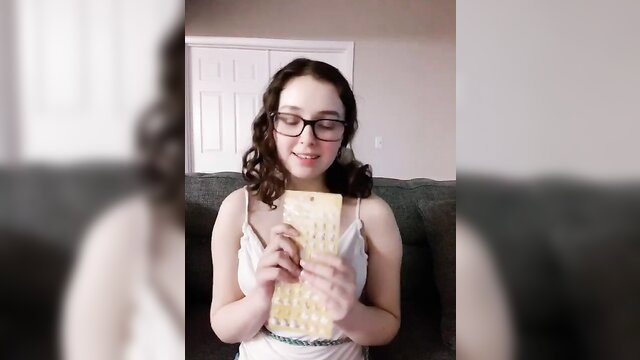 Curly-haired teen girl in white camisole holding yellow bra, smiling