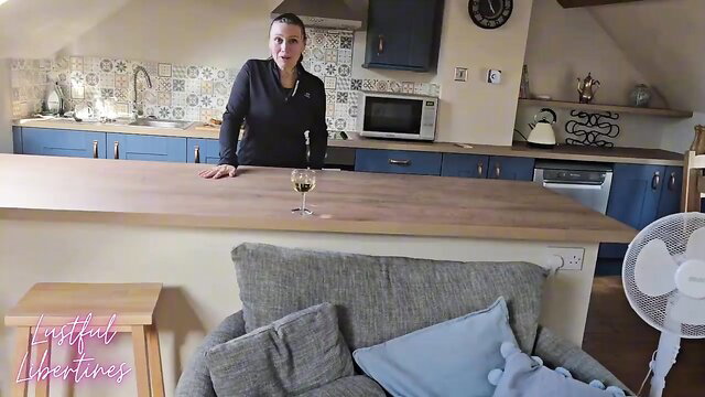 Sexy MILF massage therapist in kitchen with wine glass