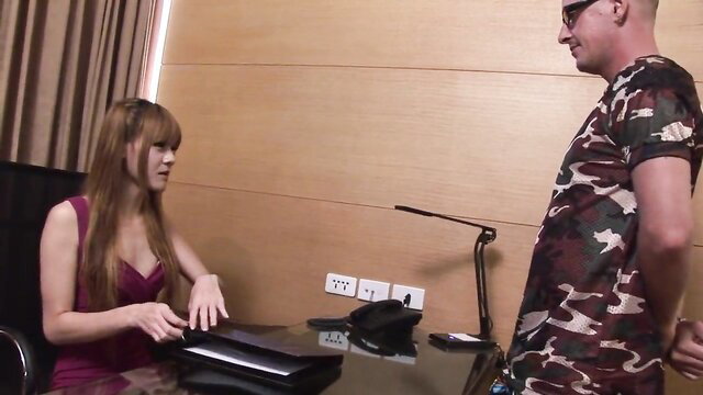 Youthful Asian trans beauty in tight dress at desk with man