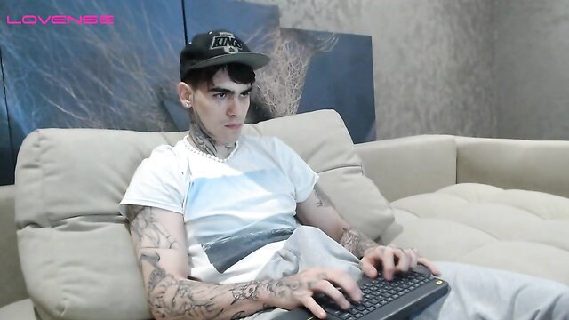 Tattooed emo guy in white tee and cap types on laptop, amateur gay thumbnail