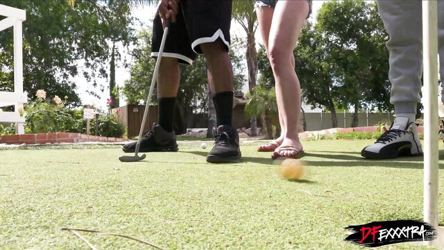 Hot blonde in shorts bends over mini golf with two black guys watching