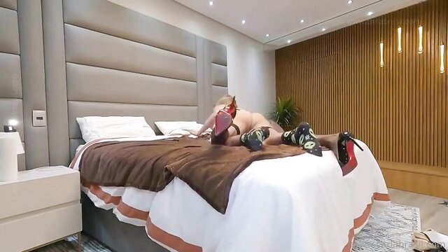 Classy Brazilian tranny with big cock on bed in red heels and socks