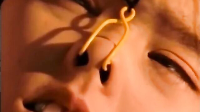 Asian woman with yellow nose clamp in shibari submission closeup