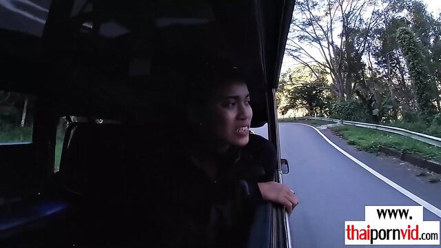 Amateur Thai teen in car window on winding road, smiling