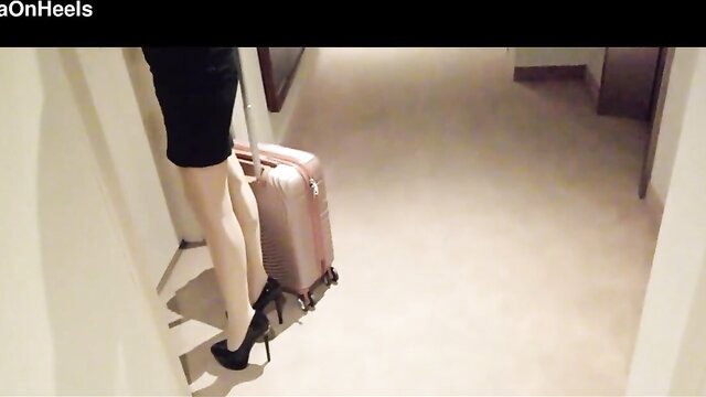 Hot MILF in nylons and heels struts hotel corridor with luggage