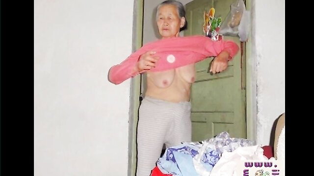 Asian granny flashing saggy tits in pink sweater and gray pants at door