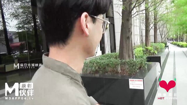 Asian man in glasses and collared shirt walking outdoors on JAV set