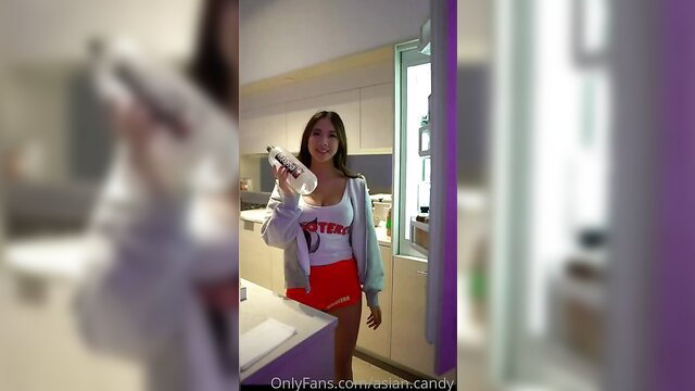 Asian Hooters girl in sexy uniform holding bottle, teasing pose