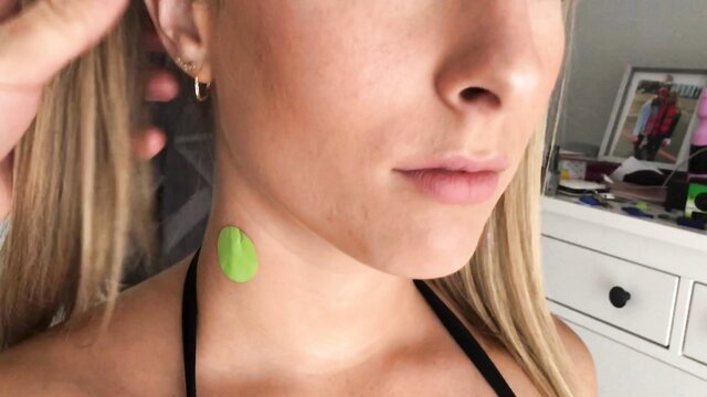 Blonde woman with green patch on neck, closeup selfie tease