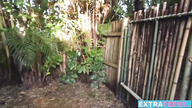 Jaye Austin by bamboo fence in lush jungle yard outdoor scene