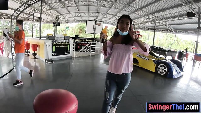 Cute Thai teen in pink top and ripped jeans posing at go-kart track