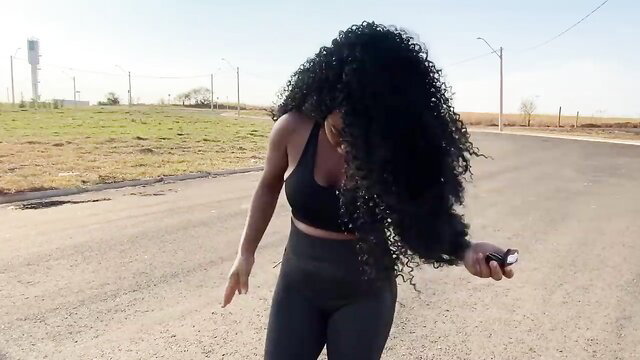 Curvy black woman in tight sports bra and leggings dances outdoors