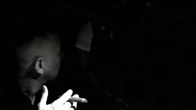 Bisexual Britni holds cigar in shadowy closeup profile