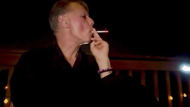 Draggin Queen smoking seductively in black dress, closeup profile