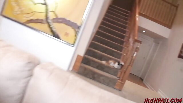 Luxury home interior with wooden stairs, beige sofa, orange tabby cat sleeping