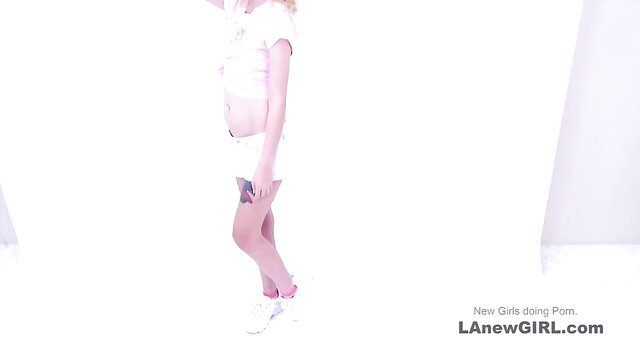 Petite blonde teen in white crop top and shorts poses sexy