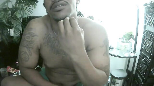 Tattooed Latino man shirtless, touching face, intense gaze in gay pride porn