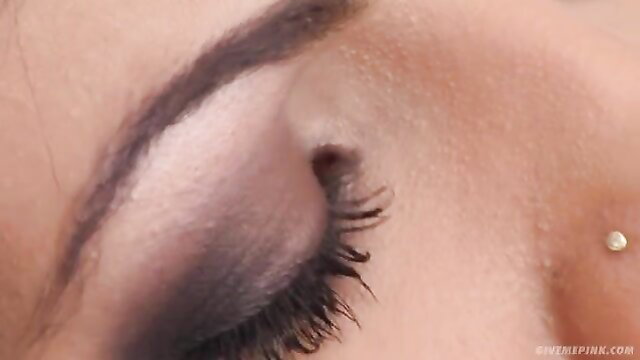 Closeup of horny brunette's smoky eye and pierced cheekbone